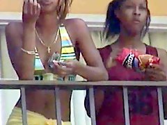 Black lesbians kissing on hotel balcony